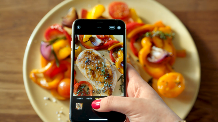 Prise d'une photo avec un Iphone d'une assiette de filet de poulet avec une poêlée de poivrons