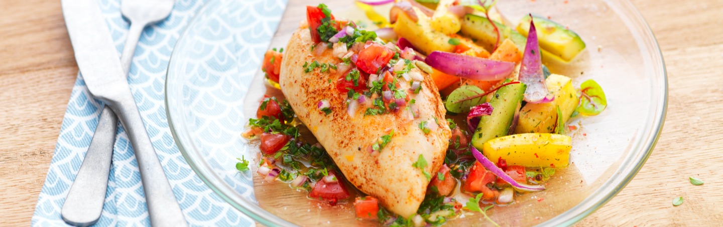 Recette de filet de poulet et ses légumes colorés disposé dans une assiette transparente